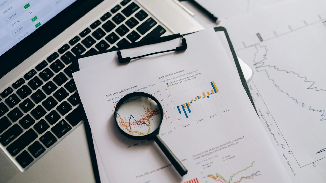 Forstørrelsesglas på dokumenter med forskellige statistiske data, der symboliserer søgen efter banker med høj indlånsrente