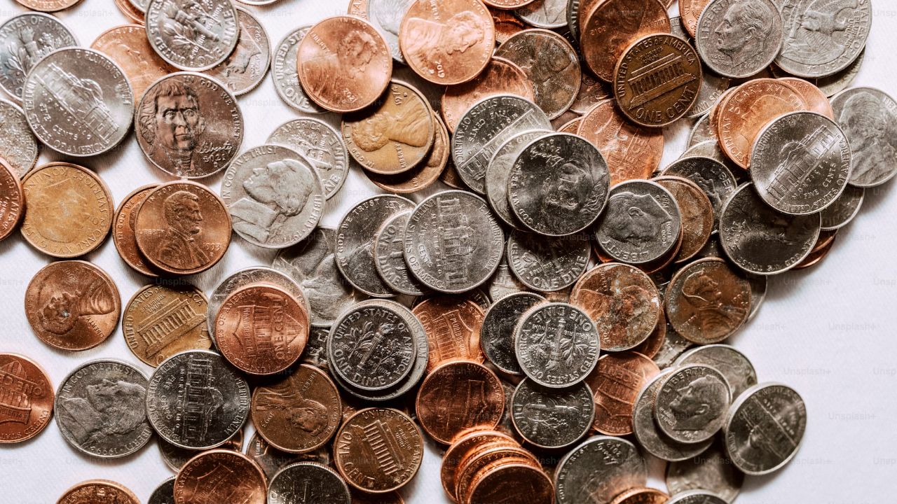 Bunke af pengemønter ligger på et bord, hvilket symboliserer overvejelserne om, hvorvidt det kan betale sig at investere 1000 kroner i aktier